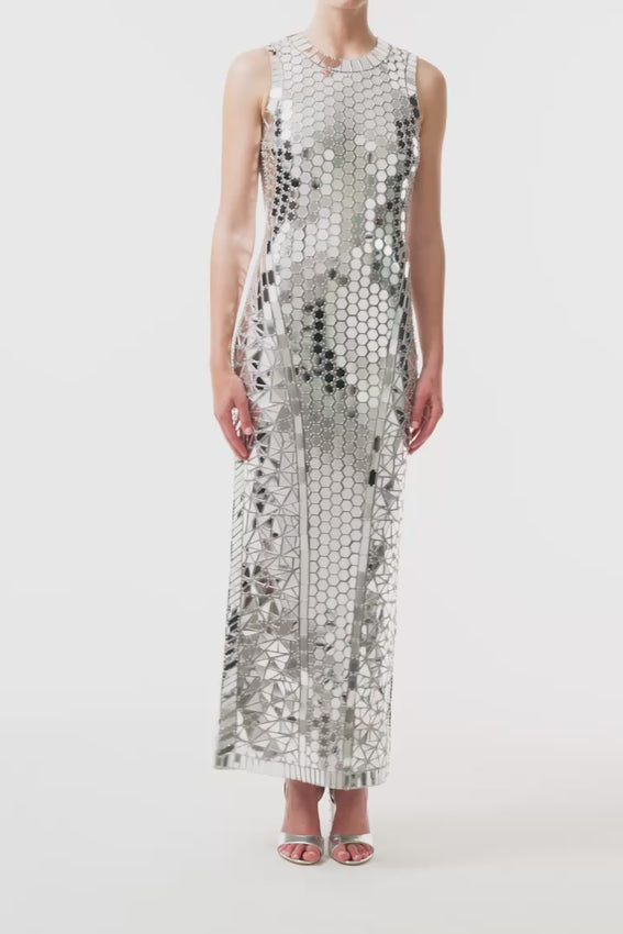 A show-stopping midi dress that commands attention with its reflective silver mirrored embroidery on delicate tulle. The jewel neckline frames the face beautifully while the form-fitting silhouette hugs your curves, with strategically placed mirrored motifs creating dimension and a sculpted look. Every movement catches light, ensuring you shimmer from every angle. Sleeveless and sophisticated—perfect for elevating your evening look.