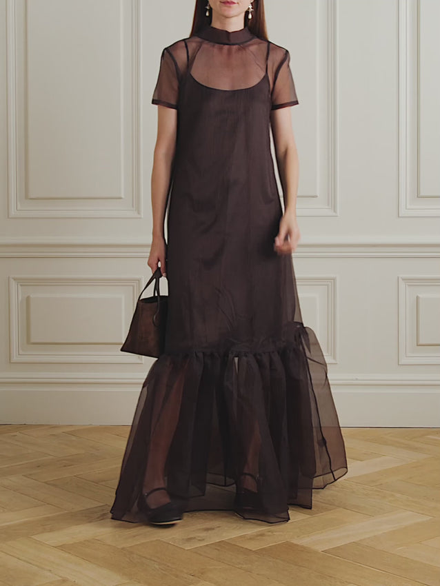 Embrace spring romance in this ethereal tiered organza maxi dress. Crafted from delicate sheer fabric, it features a relaxed silhouette with a voluminous, layered hem that moves beautifully with every step. The dramatic bow detail at the back adds an unexpected flourish, while the tonal satin slip underneath provides elegant coverage. Perfect for garden parties, weddings, or any occasion calling for effortless sophistication.