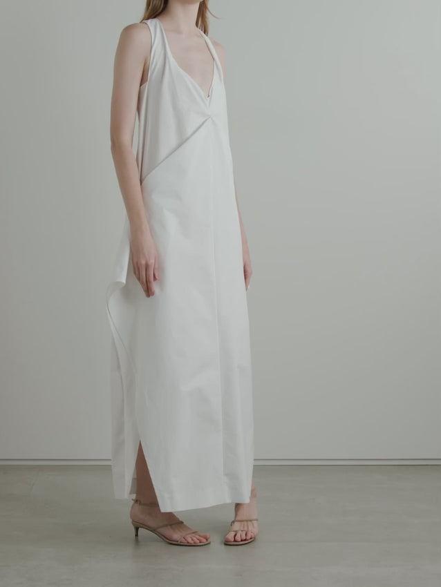 The Kenith Draped Cotton-poplin Gown embodies KHAITE's Resort '25 philosophy of refined minimalism with architectural precision. Crafted from crisp cotton-poplin, this statement piece features a daring plunging neckline and strategic side splits that balance its most striking element—a geometrically pleated skirt that commands attention through innovative construction. 