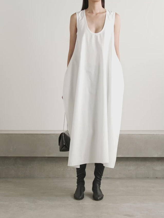 The Coli dress by Khaite embodies refined elegance through its thoughtfully designed silhouette. Crafted from crisp white cotton-poplin, this midi piece features a distinctive balloon shape that commands attention while maintaining an effortless sophistication. The unlined construction keeps the dress breathable and comfortable, while the curved hem adds a graceful finishing touch. Perfect for those who appreciate architectural design paired with accessible luxury.