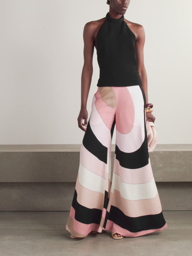 Effortlessly chic, this PUCCI jumpsuit merges the ease of separates with statement-making style. Crafted from structured cady, it features a sleek black halterneck top paired with flowing wide-leg trousers adorned in the house's iconic 'Iride' swirl print. The daring open back adds an element of allure, making this piece perfect for those seeking understated luxury with a bold edge.