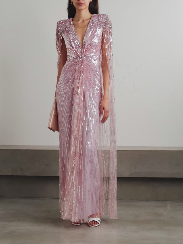 Discover timeless elegance with the 'Gold Rush' gown, where meticulous craftsmanship meets refined glamour. Shimmering beads, sequins, and crystals are strategically positioned to sculpt a flattering cinched waist, while luxurious tulle creates an ethereal silhouette. The plunging neckline is beautifully framed by padded shoulders, and a graceful cape-effect panel sweeps behind you with every movement. Lined in soft pastel-pink stretch satin for comfort and coverage, this gown embodies sophisticated luxury 